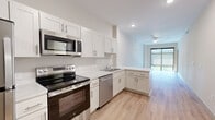 This well-appointed 2-bedroom, 1-bathroom residence in Jacksonville, Florida offers a thoughtfully designed single-floor layout with clean, modern finishes throughout. Light wood-style flooring flows seamlessly across the entire unit, contributing to a bright and cohesive aesthetic.

The kitchen is a standout feature, outfitted with white shaker-style cabinetry, light quartz countertops, and a full suite of stainless steel appliances including a range, microwave, dishwasher, and refrigerator. The L-shaped layout provides ample counter and storage space, and the kitchen opens directly into the combined dining and living area, creating a connected and functional common space.

Large floor-to-ceiling windows in the living area and bedrooms invite generous natural light while offering outdoor views. Both bedrooms are finished with ceiling fans and feature well-proportioned closets, with the primary bedroom accompanied by a walk-in closet with built-in wire shelving. The bathroom includes white cabinetry, a single vanity with a white countertop, a large mirror, and a glass-enclosed walk-in shower. Additional conveniences include a dedicated laundry area and multiple closets for extra storage throughout the unit.