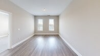 Located at 7131 Arlington Rd in the heart of Bethesda, MD, this thoughtfully designed one-bedroom, one-bathroom residence offers a efficient and modern living experience across a single floor. The open-concept kitchen is a standout feature, showcasing crisp white shaker cabinetry, a glass tile backsplash, quartz countertops, a large center island, and a full suite of stainless steel appliances including a gas range, built-in microwave, dishwasher, and French door refrigerator. Stylish pendant lighting illuminates the kitchen, adding a contemporary touch. Durable hardwood-style flooring flows throughout the main living and kitchen areas, lending warmth and cohesion to the space. The bedroom is generously proportioned, featuring plush carpeting, neutral warm-toned walls, and dual windows with blinds that invite an abundance of natural light and views of the surrounding neighborhood. A dedicated closet provides practical storage. The bathroom is clean and well-finished, featuring a full tub and shower combination with white subway tile surround, a white vanity with ample storage, and the same hardwood-style flooring found throughout the unit. The overall design palette — neutral tones, clean lines, and modern finishes — creates a bright, calm, and move-in-ready living environment.