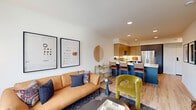 Located at 3405 SE Reed Dr. in Hillsboro, Oregon, this thoughtfully designed one-bedroom, one-bathroom residence offers a contemporary open-concept layout with efficient use of space throughout. Light wood-tone flooring flows seamlessly across the entire unit, enhancing its bright, cohesive aesthetic.

The combined kitchen and living area serves as the heart of the home. The kitchen is appointed with quartz countertops, a peninsula island with blue cabinetry and bar seating, two-tone upper cabinetry in warm wood and gray tones, a white tile backsplash, and a full suite of stainless steel appliances including a refrigerator, range, microwave, and dishwasher. Recessed lighting illuminates the space effectively.

The living area is generously proportioned with large windows that invite natural light and offer views of the surrounding neighborhood. The bedroom provides a calm, well-lit retreat with neutral tones and comfortable proportions. A dedicated closet offers practical storage with built-in shelving and hanging capacity. In-unit laundry adds everyday convenience.

The bathroom features a bold blue vanity with quartz countertop, an undermount sink, matte black fixtures, and a large mirror, delivering a polished, modern finish throughout.