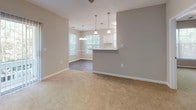 This single-floor residence offers a thoughtfully designed layout with two bedrooms and two full bathrooms. The kitchen is a standout feature, equipped with white shaker-style cabinetry, white quartz countertops, black appliances including a refrigerator, dishwasher, and microwave, and a classic subway tile backsplash. Wood-look plank flooring runs throughout the kitchen and dining area, while pendant lighting illuminates a peninsula that opens to the dining and living spaces. The living area is carpeted and bathed in natural light from large windows, with a ceiling fan overhead and sliding glass doors leading to an outdoor balcony. Both bedrooms are spacious, featuring soft carpet, ceiling fans, and windows with views of surrounding greenery. The two bathrooms are finished consistently with white vanities, quartz countertops, and wood-look plank flooring. One bathroom includes a tub-shower combo with tiled surround, while the other is accessible directly from a bedroom. Neutral wall tones and clean white trim throughout give the space a cohesive, modern aesthetic well-suited for comfortable everyday living.