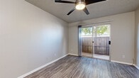 Located at 4815 E Thomas Rd in Phoenix, AZ, this thoughtfully designed one-bedroom, two-bathroom unit offers a practical and modern living experience across a single floor. The interior features consistent wood-look luxury vinyl flooring throughout, complemented by neutral gray walls and crisp white baseboards that create a clean, cohesive aesthetic.

The living room is a welcoming space equipped with a ceiling fan and a sliding glass door that opens onto a private, fenced patio, allowing natural light to flow in alongside pleasant outdoor views. The bedroom is comfortably sized, featuring its own ceiling fan, a window with blinds, and ample room for furnishings.

The galley-style kitchen is well-appointed with white shaker cabinetry, subway tile backsplash, light quartz-style countertops, and a full suite of stainless steel appliances, including a refrigerator, range, microwave, and dishwasher — offering both style and functionality in a compact, efficient layout.

The two bathrooms are clean and updated; one features a floating wood-toned vanity with a white countertop and a large mirror, while the other includes a full tub-shower combination. A dedicated closet provides additional storage. Textured ceilings with ceiling fans throughout complete the practical, move-in-ready character of this Phoenix residence.