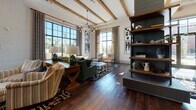 Located at 20 Romney St in Charleston's historic 29403 zip code, this single-floor communal space showcases an expertly curated blend of Southern character and contemporary design. Soaring ceilings with exposed wood beams set the tone throughout, while rich, wide-plank hardwood floors anchor each distinct area with warmth and continuity.

The expansive main lounge is anchored by a dramatic shiplap fireplace clad in deep navy tile, topped with a mounted display and flanked by open industrial-style shelving. Large steel-framed windows flood the space with natural light and offer views of the surrounding landscape. Eclectic seating arrangements — featuring velvet green sofas, floral accent chairs, and woven textiles — create an inviting, residential atmosphere.

A dedicated coffee and refreshment bar, framed by sage-green shiplap and pendant lighting, provides a comfortable retreat. Adjacent to this is a built-in desk nook and a glass-walled conference room with floral-etched panels, offering private workspace options. The fully equipped kitchen features teal cabinetry, a generous white quartz island, stainless steel appliances, and rich wood accents. A dining area with a gallery wall of curated artwork completes this beautifully layered, community-focused space.