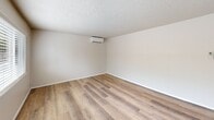 Located in Lakewood, WA, this two-bedroom, two-bathroom home spans two equally sized floors, offering a well-organized and functional layout. The main level features a bright living room with light-toned luxury vinyl plank flooring and a sidelight entry door that lets in natural light. The kitchen is equipped with warm honey-toned wood cabinetry, dark countertops, and white appliances including a dishwasher, electric range, and refrigerator, complemented by tile flooring. A stacked washer and dryer unit is conveniently housed within the kitchen area. Both bathrooms include tile flooring, with one featuring a bathtub and textured surround. Upstairs, two carpeted bedrooms each offer natural window views and generous closet space with sliding and panel-style doors. The primary bedroom includes a wall-mounted mini-split unit for independent climate control. A hallway connects the upper-level rooms, with staircase access visible through an open railing. Textured ceilings are consistent throughout the home. With four closets distributed across both floors, storage is ample. The overall aesthetic is clean and neutral, making for a move-in ready space.
