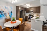 Located at 310 S Jefferson St in Placentia, California, this single-story residence offers a well-designed layout with a cohesive, contemporary aesthetic throughout. The living room is a welcoming space featuring light wood-style flooring, neutral walls, and generous natural light filtered through sheer curtains. Thoughtful design touches, including a starburst wall mirror and colorful artwork, lend warmth and character to the room.

The kitchen is outfitted with dark wood-tone cabinetry, white countertops, a subway tile backsplash, and a full suite of stainless steel appliances including a refrigerator, range, and microwave. A dedicated dining area adjacent to the kitchen provides an intimate setting accented by bold abstract artwork and modern decorative wall pieces.

The unit includes two bedrooms, each with wood-style flooring, soft neutral tones, and large windows that invite natural light. Both rooms offer ample space and stylish décor. The bathrooms feature dark wood vanities, white countertops, large mirrors, and clean, modern finishes.

A convenient in-unit laundry area houses a stacked full-size washer and dryer alongside built-in cabinetry for additional storage. The overall ambiance of this residence is modern, bright, and well-appointed, making it an inviting home in the heart of Placentia.