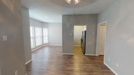 This single-story home offers a thoughtfully designed layout that balances open communal spaces with comfortable private quarters. The main living and dining areas are connected by hardwood-style flooring in warm tones, complemented by neutral gray walls and textured ceilings. A decorative light fixture anchors the dining area, while multiple windows fitted with blinds allow natural light to fill the space. A sliding glass door in the living room provides additional brightness and outdoor access.

The kitchen is accessible via an arched opening and features a galley-style layout with white cabinetry, granite-look countertops, and stainless steel appliances including a refrigerator and electric range. Light wood-tone flooring ties the kitchen seamlessly to the adjoining areas.

The bedrooms are finished with plush neutral carpeting and ceiling fan fixtures, each room benefiting from natural light through blinds-covered windows. Closet access is conveniently located within each room.

The bathrooms are well-appointed with wood-style vinyl flooring, white vanity cabinetry topped with granite-patterned countertops, a large mirror, and a full tub-shower combination. Chrome fixtures and towel bars add a clean, modern finishing touch throughout. Overall, the home presents a cohesive, move-in-ready aesthetic.