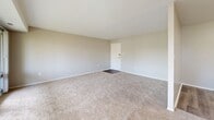 Located at 14801 Bowie Rd in Laurel, MD, this single-floor unit offers a well-organized layout across three bedrooms and two bathrooms. The living room is a standout space, featuring large sliding glass doors that span nearly the full width of the wall, providing abundant natural light and direct access to a balcony overlooking mature trees. Neutral-toned carpet and clean white walls give the living area a bright, open feel.

The kitchen is equipped with warm-toned wood cabinetry, granite-style countertops, a gas range, and a full-size refrigerator, all finished in black. Light wood-style flooring runs throughout the kitchen, which opens conveniently into the main living area.

Each of the three bedrooms features plush carpeting and windows that allow natural light to filter in. The primary bedroom includes a set of louvered bi-fold closet doors offering generous storage. The secondary bedrooms are similarly carpeted with neutral walls.

The two bathrooms are cleanly finished; one features a tub-shower combo with tile surround accented by a decorative mosaic border, while the other includes a granite-top vanity with a medicine cabinet mirror.