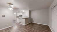 This single-floor, one-bedroom, one-bathroom unit offers a practical and well-organized layout designed to maximize every square foot of its compact footprint. Consistent wood-look laminate flooring flows throughout the living areas and bedroom, providing a warm and cohesive aesthetic that complements the neutral gray wall tones and crisp white baseboards found throughout.

The living room is a bright, open space featuring a ceiling fan with light fixture, a front entry door, and a window fitted with horizontal blinds that allow for natural light control. The room's clean lines and understated palette create a versatile canvas ready for personalization.

The kitchen area is visible in the floorplan view and includes light-colored countertops with a pass-through or breakfast bar element, along with white cabinetry, making efficient use of the available space.

The bedroom is a well-proportioned private retreat, also finished with wood-look flooring and neutral walls. It features a ceiling fan with lighting, a window with blinds for natural light, and a six-panel door that leads conveniently to the bathroom.

The bathroom is finished with beige ceramic tile surround in the tub/shower combination, complemented by tile flooring, and includes a standard toilet and full-size soaking tub, offering a clean and functional space. Overall, the unit presents a move-in ready, low-maintenance living environment.