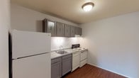 Unit #19 at 1391 is a single-story residence offering a practical and straightforward layout across several distinct spaces. The kitchen is equipped with gray cabinetry — both upper and lower — paired with a white tile backsplash, laminate countertops, a double-basin sink, a white electric coil range, a dishwasher, and a full-size refrigerator. Wood-look flooring grounds the kitchen area, providing a clean contrast to the surrounding neutral walls.

A carpeted hallway connects the main living areas, leading to the bedrooms and bathroom. The living area is generously proportioned, featuring plush carpet, neutral painted walls, and a sliding glass door that brings in natural light and provides access to an outdoor space with exterior views of surrounding greenery.

The bedrooms are carpeted and finished with neutral walls, offering a calm and functional environment. One bedroom includes a window with an outdoor view, while another benefits from the natural light provided by the sliding glass door. The bathroom features a tiled tub and shower combination enclosed by a sliding glass door, white tile wainscoting, and standard fixtures, presenting a clean and functional design. Overall, the unit maintains a neutral, move-in ready aesthetic throughout.