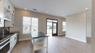 Located in Decatur, GA, this single-floor unit showcases a thoughtfully designed interior with a clean, modern aesthetic. The kitchen is a standout feature, boasting floor-to-ceiling white shaker cabinets, bold dark countertops, a striking black penny-tile backsplash, stainless steel appliances including a refrigerator with ice maker, electric range, and over-the-range microwave, and a stainless steel sink. A central island with a dark countertop provides additional prep and casual dining space. Light hardwood-style flooring flows seamlessly from the kitchen into the open living area, which is bathed in natural light from multiple windows fitted with horizontal blinds. A glass-panel door opens directly onto a private balcony, offering views of the surrounding Decatur neighborhood. The spacious living area features recessed lighting and a neutral color palette that enhances the airy, open feel of the space. The bathroom is well-appointed with a subway-tiled soaking tub and shower combination, a dark-countered vanity with black hardware, and tile flooring. Bold dark-framed doors throughout the unit add a striking architectural contrast to the light interior, contributing to the contemporary character of this well-finished Decatur residence.