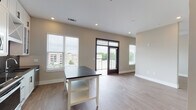 Located in Decatur, GA, this single-floor unit showcases a thoughtfully designed interior with a clean, modern aesthetic. The kitchen is a standout feature, boasting floor-to-ceiling white shaker cabinets, bold dark countertops, a striking black penny-tile backsplash, stainless steel appliances including a refrigerator with ice maker, electric range, and over-the-range microwave, and a stainless steel sink. A central island with a dark countertop provides additional prep and casual dining space. Light hardwood-style flooring flows seamlessly from the kitchen into the open living area, which is bathed in natural light from multiple windows fitted with horizontal blinds. A glass-panel door opens directly onto a private balcony, offering views of the surrounding Decatur neighborhood. The spacious living area features recessed lighting and a neutral color palette that enhances the airy, open feel of the space. The bathroom is well-appointed with a subway-tiled soaking tub and shower combination, a dark-countered vanity with black hardware, and tile flooring. Bold dark-framed doors throughout the unit add a striking architectural contrast to the light interior, contributing to the contemporary character of this well-finished Decatur residence.