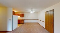 This single-floor unit offers a straightforward, functional layout designed for comfortable everyday living. The open living and dining area is generously sized, featuring neutral-toned carpet underfoot and a ceiling fan with light fixture overhead. A sliding glass door connects the living space to the outdoors, allowing natural light to fill the room. The kitchen is positioned at one end of the open-plan area and is equipped with warm medium-toned oak cabinetry, a double sink, laminate countertops, tile flooring, and a white refrigerator. Ample upper and lower cabinet storage makes the kitchen highly practical.

The bedrooms are carpeted and well-proportioned, each featuring windows that frame views of surrounding greenery, wood-trimmed window frames, and baseboard heating units along the walls. Some bedrooms also include wall-mounted air conditioning units for individual climate control.

Two bathrooms serve the unit. One features a shower enclosure with sliding glass doors, an oak vanity with a single sink, and a wide wall mirror. The second bathroom offers a full bathtub with a curved shower rod, a matching oak vanity, and tile flooring. Throughout the unit, warm oak-toned doors and trim provide a consistent, cohesive aesthetic against the light-colored walls.