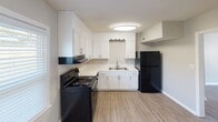 Located at 2352 Pineview Ln in Gastonia, NC, this two-story home offers a well-organized layout spread across two levels, connected by an interior staircase. The kitchen is a functional highlight, featuring crisp white cabinetry, light-toned countertops, a double-basin sink, and black appliances including a range with overhead ventilation and a full-size refrigerator. Light wood-look flooring runs through the kitchen, adding warmth and easy maintenance. The living areas on the main level continue with durable hard surface flooring and ceiling fans with integrated lighting, contributing to a comfortable, practical atmosphere. Natural light filters in through blinded windows throughout the home, brightening each room. Bedrooms are finished with soft carpeting and ceiling fans, providing a cozy retreat. The bathroom is cleanly appointed with a white vanity, round sink basin, framed mirror, wall sconce lighting, and a full tub-shower combination with a curtain rod, all set on wood-look flooring. Neutral gray tones are carried consistently throughout the home, creating a cohesive and move-in-ready aesthetic. Textured ceilings are present throughout, adding a traditional finish to the space.