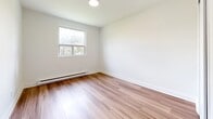 Located at 1 Slessor Blvd in Grimsby, Ontario, this well-designed 2-bedroom, 1-bathroom unit offers a thoughtfully laid-out single-floor plan with a clean, modern aesthetic. Warm-toned hardwood flooring flows consistently throughout the space, complementing crisp white walls and clean baseboards to create a bright, cohesive interior.

The kitchen is a functional highlight, featuring white upper cabinetry, dark lower cabinets, a light stone countertop with a peninsula overhang, and a full suite of stainless steel appliances including a refrigerator, stove, microwave, and dishwasher. Recessed lighting above adds a polished finish.

The open living area is generously sized, offering ample natural light and a versatile layout. The primary bedroom is a comfortable, well-proportioned room with a large sliding window overlooking greenery, a built-in closet, and baseboard heating. The second bedroom also benefits from natural light through a window with outdoor views and its own baseboard heater.

The bathroom is finished in clean white tile, featuring a full soaker tub with an overhead shower, a dark-cabinetry vanity with a stone countertop, and a window for natural ventilation. Throughout the unit, the design prioritizes simplicity, functionality, and a bright, welcoming atmosphere.