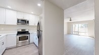 This single-story, 2-bedroom, 1-bathroom residence in La Mesa, California offers a thoughtfully designed layout across a comfortable footprint. Light-toned, wood-style flooring runs consistently throughout, creating a cohesive and clean aesthetic in every room.

The living room is a standout feature, benefiting from a ceiling fan and a full-width sliding glass door that opens to a private balcony, allowing abundant natural light and outdoor views to define the space. A second sliding glass door in an adjacent area further enhances the indoor-outdoor connection.

The kitchen is efficiently laid out and features white shaker-style cabinetry, white quartz countertops, a deep stainless steel undermount sink with a pull-down faucet, and stainless steel appliances including a range, microwave, refrigerator, and dishwasher. A window above the sink provides natural light.

The spacious primary bedroom includes a mirrored sliding closet and connects seamlessly to the rest of the unit via a hallway. The second bedroom is well-proportioned and also features a sliding closet. Both bedrooms are finished with neutral tones and the same wood-style flooring, maintaining a consistent, modern feel throughout the residence.