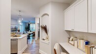 Located at 601 Gilcrest Farm Rd in Wake Forest, NC, this thoughtfully designed 2-bedroom, 2-bathroom home offers a well-appointed single-floor layout. The kitchen is a standout feature, showcasing white shaker cabinetry extending to the ceiling, a classic subway tile backsplash, quartz countertops, and a full suite of stainless steel appliances. A large center island with pendant lighting and bar seating makes it ideal for both cooking and entertaining. A built-in desk nook with cabinetry and a charming arched wall alcove add character to the transitional space leading toward the living area. The living room is bright and welcoming, with natural light filtering through large windows and a ceiling fan overhead. Both bedrooms feature ceiling fans, natural light, and bold accent walls that lend a modern, curated feel. The primary bedroom is generously sized with ample space for a full suite of furnishings. The primary bathroom includes a dual-sink vanity, glass-enclosed shower, and wood-look flooring. A dedicated laundry room with full-size washer and dryer hookups adds everyday convenience. Wood-look flooring flows throughout, tying together the home's clean, contemporary aesthetic.