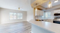This well-appointed single-floor residence offers a thoughtfully designed open-concept layout with a seamless flow between the living and kitchen areas. The living space features wood-look flooring, a ceiling fan, and generous natural light streaming through multiple windows fitted with blinds. An elegant arched architectural detail frames the transition between rooms, adding a classic design touch.

The kitchen is a functional centerpiece, showcasing white shaker-style cabinetry, bright quartz countertops, a subway tile backsplash, stainless steel appliances including a dishwasher, microwave, and range, and a peninsula with a deep single-basin sink accented by a brushed gold faucet. Pendant lighting with gold-toned fixtures adds warmth overhead.

The bedrooms are carpeted and well-sized, each benefiting from natural light via windows with blinds. One bedroom offers direct access to a private outdoor balcony with exterior views. The bathrooms are cleanly finished — one features a marble-topped vanity with white cabinetry, a gold faucet, and a large mirror, while a second includes a full soaking tub and shower combination. Throughout, the neutral warm-beige palette creates a cohesive, inviting atmosphere.