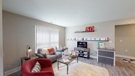 This single-floor residence at Enclave 50 offers a thoughtfully designed layout that balances comfort and functionality. The living room serves as the central gathering space, featuring light wood-style flooring, neutral warm-gray walls, and large windows with vertical blinds that allow ample natural light. The room accommodates a comfortable seating arrangement alongside a media console and display shelving.

The kitchen is well-equipped with white shaker-style cabinetry, granite-patterned countertops, a peninsula with additional counter seating, and a full suite of stainless steel appliances, including a gas range, microwave, and refrigerator. Recessed lighting and a pendant fixture over the peninsula enhance the bright, clean aesthetic.

Adjacent to the kitchen, the dining area features light hardwood-style flooring, a glass-top table with modern chairs, and large windows that flood the space with natural light.

The bedroom offers plush carpeting, a large window, and a wall-mounted shelf, creating a calm and practical retreat. The full bathroom includes a granite-topped vanity with white cabinetry, a large mirror, and tile flooring. A dedicated laundry area houses a full-size washer and dryer with overhead shelving for additional storage.