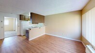 This single-floor unit at 12605 Maple View in Lakeside offers a practical, well-organized layout connecting the main living spaces efficiently. The living area features warm hardwood-style flooring, a textured ceiling, and a ceiling fan with light fixture. A large window dressed with vertical blinds allows natural light to fill the room, while a wall-mounted AC unit provides climate control. The front entry door opens directly into this welcoming main space.

The kitchen is positioned adjacent to the living area and separated by a peninsula counter with barstool clearance, offering an open, connected feel. Dark wood cabinetry provides ample upper and lower storage, complemented by white appliances including a refrigerator, range, and dishwasher. Light-toned countertops and a single-basin sink complete the functional workspace, all set on matching hardwood-style flooring.

The bedroom is a generously sized, carpeted room featuring its own ceiling fan, a wide window with vertical blinds for natural light, and neutral-toned walls that create a calm atmosphere.

The bathroom includes a full-size soaking tub with an overhead shower, chrome fixtures, and a small window above the tub that brings in natural light. The overall ambiance of the unit is clean, practical, and well-lit throughout.
