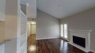 Located at 2742 Jeanetta St in Houston's 77063 zip code, this single-floor residence offers a well-appointed layout with a blend of practical design and comfortable living spaces. The living room immediately impresses with its soaring vaulted ceilings, rich dark hardwood-style flooring, and a classic white-mantled fireplace flanked by French doors and sidelights that invite abundant natural light and provide access to an outdoor balcony area. Built-in shelving adds functional charm to one corner of the room. A central hallway connects the living areas to the rest of the home, where the kitchen features dark espresso cabinetry, granite-look countertops, and black appliances including a range, microwave, dishwasher, and refrigerator, all illuminated by overhead lighting. The bedrooms are finished with plush carpeting; one includes a ceiling fan and a large sliding glass door opening to an outdoor balcony with views of surrounding greenery. The bathrooms are clean and functional, each equipped with a tub-shower combination with tiled surround and hardwood-style flooring. Neutral warm-gray walls throughout the home create a cohesive, move-in-ready aesthetic suited for a variety of furnishing styles.