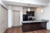 Located at 10063 S Creek Run Way in Sandy, Utah, this single-floor residence offers a well-designed layout that balances comfort and functionality. The kitchen serves as a central highlight, featuring a granite countertop peninsula with a double basin sink, dark espresso cabinetry, black appliances including a refrigerator, electric range, and microwave, and warm hardwood flooring that extends throughout the main living areas. Pendant lighting above the peninsula and track lighting overhead add both task illumination and a modern aesthetic.

The open layout connects the kitchen seamlessly to the living area, where hardwood floors continue and additional track lighting provides a bright, welcoming atmosphere. Doors lead to a laundry area and additional rooms, keeping the layout practical and accessible.

The bedrooms are carpeted for comfort and feature ceiling fans with light fixtures and windows that invite natural light and outdoor views of the surrounding Sandy landscape. One bedroom benefits from dual windows, enhancing its brightness and ventilation.

Two bathrooms complete the unit — one with a walk-in shower and granite-topped vanity, the other with a full tub-shower combination — both finished with neutral tile flooring. The cohesive design throughout emphasizes clean lines and a neutral color palette.