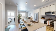 Located at 2287 Welton St in Denver's vibrant Five Points neighborhood, this thoughtfully designed one-bedroom, two-bathroom residence offers a modern and efficient layout across a single floor. The open-concept living and kitchen area serves as the heart of the home, featuring light hardwood flooring, recessed lighting, and a seamless flow between spaces. The kitchen is outfitted with crisp white cabinetry extending to the ceiling, a grey tile backsplash, stainless steel appliances including a French door refrigerator and range, and a generous quartz-topped island with bar seating — ideal for both cooking and entertaining. The living room is bathed in natural light from a large sliding glass door that opens to a private balcony with sweeping Denver city views. The bedroom is a serene retreat, offering a sizable window framing the city skyline, plush carpeting, and ample space for furnishings. Two well-appointed bathrooms include a full bath with a subway-tiled tub/shower combo and modern vanity. A dedicated closet, hallway, and efficient floor plan round out this polished urban residence, delivering comfort and contemporary style in equal measure.