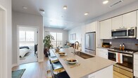 Located at 2287 Welton St in Denver's vibrant Five Points neighborhood, this thoughtfully designed one-bedroom, two-bathroom residence offers a modern and efficient layout across a single floor. The open-concept living and kitchen area serves as the heart of the home, featuring light hardwood flooring, recessed lighting, and a seamless flow between spaces. The kitchen is outfitted with crisp white cabinetry extending to the ceiling, a grey tile backsplash, stainless steel appliances including a French door refrigerator and range, and a generous quartz-topped island with bar seating — ideal for both cooking and entertaining. The living room is bathed in natural light from a large sliding glass door that opens to a private balcony with sweeping Denver city views. The bedroom is a serene retreat, offering a sizable window framing the city skyline, plush carpeting, and ample space for furnishings. Two well-appointed bathrooms include a full bath with a subway-tiled tub/shower combo and modern vanity. A dedicated closet, hallway, and efficient floor plan round out this polished urban residence, delivering comfort and contemporary style in equal measure.