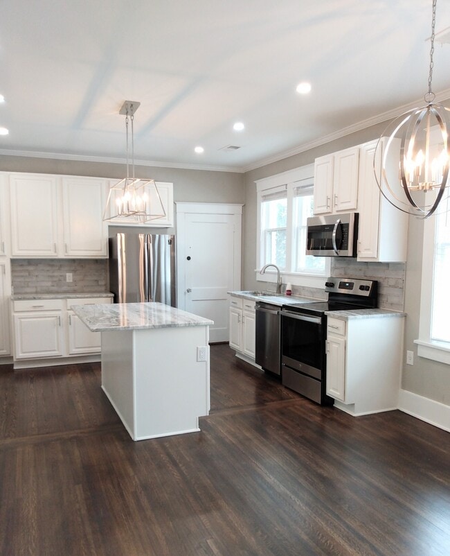 Modern kitchen with stainless steel appliances and granite island. - 285 Hawthorne St