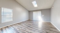 Located at 2260 W 76th Ave in Denver, CO, this 2-bedroom, 1-bathroom single-story home offers a thoughtfully arranged floor plan with modern finishes throughout. The living room is a standout space, featuring soaring vaulted ceilings, a skylight that floods the room with natural light, and light wood-style flooring that extends seamlessly into the kitchen. Vaulted ceilings and a sliding glass door with vertical blinds add to the airy, open feel of the main living area. The kitchen is well-appointed with white shaker cabinetry, granite-style countertops, black appliances, and a peninsula that opens toward the living space, creating an efficient and connected layout. The full bathroom includes a granite-top vanity with white cabinetry and a tub/shower combination. Both bedrooms are carpeted and finished with soft grey walls and window blinds, providing a quiet and comfortable retreat. The primary bedroom offers generous proportions with natural light, while the second bedroom is equally well-lit. Additional spaces include four closets for ample storage, a dedicated laundry area, and a hallway connecting all rooms. The consistent use of light tones and wood-style flooring creates a cohesive, clean aesthetic throughout.