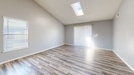 Located at 2260 W 76th Ave in Denver, CO, this 2-bedroom, 1-bathroom single-story home offers a thoughtfully arranged floor plan with modern finishes throughout. The living room is a standout space, featuring soaring vaulted ceilings, a skylight that floods the room with natural light, and light wood-style flooring that extends seamlessly into the kitchen. Vaulted ceilings and a sliding glass door with vertical blinds add to the airy, open feel of the main living area. The kitchen is well-appointed with white shaker cabinetry, granite-style countertops, black appliances, and a peninsula that opens toward the living space, creating an efficient and connected layout. The full bathroom includes a granite-top vanity with white cabinetry and a tub/shower combination. Both bedrooms are carpeted and finished with soft grey walls and window blinds, providing a quiet and comfortable retreat. The primary bedroom offers generous proportions with natural light, while the second bedroom is equally well-lit. Additional spaces include four closets for ample storage, a dedicated laundry area, and a hallway connecting all rooms. The consistent use of light tones and wood-style flooring creates a cohesive, clean aesthetic throughout.