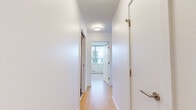 This efficient two-bedroom, two-bathroom high-rise unit offers a well-designed layout that maximizes every square foot of its single-floor footprint. The open-concept kitchen and dining area serves as the heart of the home, featuring a central island with granite countertops and an integrated sink, stainless steel appliances including a range, microwave, and refrigerator, and recessed lighting throughout. Floor-to-ceiling windows flood the living and dining area with natural light while framing impressive panoramic city skyline views.

Light-toned hardwood flooring runs throughout the main living areas, complementing the clean white walls and modern aesthetic. A well-proportioned hallway connects the bedrooms and bathrooms, featuring a flush ceiling fixture and sliding doors. Both bedrooms are bright and airy, each equipped with large windows that frame striking urban vistas and baseboard heating units.

The bathrooms are finished with contemporary fixtures, including one featuring a floating white vanity with granite countertops, a medicine cabinet mirror, large-format dark tile flooring, and a grab bar. The second bathroom includes a soaking tub enclosed by crisp white subway tile. The overall design is clean, modern, and functional, making excellent use of the available space.