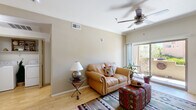 This thoughtfully designed single-floor residence offers a comfortable and cohesive layout across its one bedroom, one bathroom, kitchen, living room, hallway, and closet. The living room serves as the heart of the home, featuring light hardwood-style flooring, crown molding, a ceiling fan, and a large sliding glass door that floods the space with natural light and opens to an outdoor balcony area with greenery views. The kitchen is well-equipped with rich dark wood cabinetry extending to the ceiling, granite-style countertops, black appliances including a gas range and built-in microwave, a double sink, and tile flooring — all accented by track lighting and decorative crown molding. The bedroom offers a calm, airy retreat with plush carpet, a bay-style window with a built-in ledge seat, and ample space for generous furnishings. The bathroom features tile-surround tub and shower combination, granite-topped vanity with dark wood cabinetry, and light tile flooring. Throughout the residence, a warm Southwestern aesthetic is carried by earthy tones, neutral walls, and natural textures, creating an inviting and cohesive ambiance from room to room.