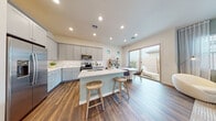 This well-designed single-floor residence offers a cohesive blend of modern style and functional living. The heart of the home is the open-concept kitchen, which features gray shaker-style cabinetry, white quartz countertops, and a full suite of stainless steel appliances including a refrigerator, range, microwave, and dishwasher. A central island with bar seating serves as both a prep space and casual dining area, while rich wood-look flooring flows seamlessly throughout. A sliding glass door connects the kitchen and dining area directly to an outdoor patio, filling the space with natural light and providing easy indoor-outdoor access. The living room is bright and welcoming, highlighted by soft sage-green accent walls, sheer curtains framing large windows, and warm wood-tone flooring that ties the space together. The bedrooms continue the calming aesthetic with coordinating accent walls, generous natural light from well-placed windows, and ample room for comfortable furnishings. The bathroom is finished in crisp white, featuring a wide vanity with an undermount sink, a frameless glass walk-in shower, and a window that brings in additional natural light. Throughout the home, recessed lighting and a neutral color palette create a bright, airy atmosphere with a consistently modern and inviting character.