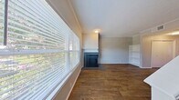 This contemporary townhome in Carrollton, TX offers a well-designed living space across two floors. The 890 square foot interior showcases an open concept layout, maximizing the use of space. The ground floor features a bright living room with a sleek fireplace and large windows, allowing natural light to flood the space. The modern kitchen boasts dark grey cabinetry, stainless steel appliances, granite countertops, and a subway tile backsplash, creating a stylish cooking environment. Hardwood flooring runs throughout, adding warmth and continuity to the home. The primary bedroom, measuring 140 square feet, provides ample space and includes a ceiling fan for comfort. All three bathrooms feature updated fixtures and granite countertops. Additional amenities include built-in shelving, closet space, and a sliding glass door leading to an outdoor area. The neutral color palette and textured ceilings contribute to the home's contemporary aesthetic, making it an ideal space for modern living.