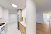 Located at 10155 116 St NW in Edmonton's vibrant Oliver neighbourhood, this 2-bedroom, 1-bathroom unit offers a thoughtfully designed single-floor layout with a clean, modern aesthetic throughout. Light hardwood flooring runs continuously across the living, dining, and bedroom areas, creating a cohesive and warm atmosphere.

The open living and dining area is generously proportioned, with white walls and a neutral palette that maximize the sense of space. The renovated kitchen features a striking combination of warm wood cabinetry and crisp white upper cabinets, complemented by a white marble-effect countertop and stainless steel appliances — a standout design element in the unit.

The primary bedroom is a well-sized room with a large window offering city views and a mirrored sliding closet that enhances the sense of depth and light. The second bedroom is bright and comfortable, also featuring a window with natural light and baseboard heating. With four closets spread across the unit, storage is well-accommodated throughout.

The bathroom is finished with large-format neutral tiles surrounding a full soaker tub and shower, maintaining the unit's clean, contemporary feel. Multiple hallways connect the rooms efficiently, and the overall layout is practical and well-organized for everyday living.