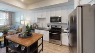 Located at 5377 Quail Run Rd in Riverside, California, this single-story residence offers a thoughtfully designed layout with modern finishes and a warm, inviting ambiance. The kitchen is a standout feature, showcasing white shaker cabinetry extending to the ceiling, a classic subway tile backsplash, dark countertops, and a full suite of stainless steel appliances including a gas range, built-in microwave, dishwasher, and refrigerator. Wood-look flooring runs throughout the main living areas, adding warmth and continuity to the space. The living room benefits from an abundance of natural light streaming through large windows dressed with blinds and patterned drapes, creating a bright and welcoming atmosphere. The bedrooms are carpeted for comfort, each featuring ceiling fans, generous windows with blinds, and ample space for furnishings. The bathroom is finished with white cabinetry, a dark countertop vanity, a large mirror, wood-look tile flooring, and a full tub and shower combination. Throughout the residence, a neutral color palette and clean architectural lines contribute to a cohesive, contemporary aesthetic that is both functional and visually appealing.