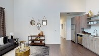This two-story, 2-bedroom, 2-bathroom townhome offers a well-designed layout across two levels, combining modern aesthetics with functional living spaces. The interior showcases striking soaring ceilings that lend an airy, expansive feel to the main living area, complemented by rich hardwood-style flooring that flows seamlessly throughout. Clean white walls and thoughtfully placed décor accents create a bright, welcoming ambiance. The open-concept design connects the living area to the kitchen, which is equipped with stainless steel appliances, including a full-size refrigerator, and features warm wood-toned cabinetry. The layout provides a natural sense of flow between spaces, making the home ideal for both everyday living and entertaining. Outside, the townhome boasts a generously sized private backyard enclosed by a full-height wooden privacy fence, offering a secluded outdoor retreat with a well-maintained green lawn and a young shade tree. The exterior of the building presents a contemporary board-and-batten siding design in a neutral gray palette, contributing to its modern curb appeal. With a dedicated HVAC unit and multiple windows allowing natural light to filter in, this townhome blends comfort, style, and practicality in a cohesive package.