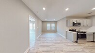 Located at 1207 E Armour Blvd in Kansas City, Missouri, this thoughtfully renovated apartment on the second floor offers a clean, contemporary aesthetic throughout its single-level layout. Light wood-tone luxury flooring runs seamlessly across the entire unit, creating a bright and cohesive feel in every room. The open living and dining area is bathed in natural light from multiple windows fitted with white horizontal blinds, complemented by recessed lighting that illuminates the neutral gray walls and crisp white trim. The kitchen is efficiently designed and features stainless steel appliances including a range, over-the-range microwave, and dishwasher, paired with gray shaker-style cabinetry, white quartz countertops, and a classic white subway tile backsplash. The bedroom is a comfortable, well-lit retreat with dual windows and a ceiling fan with integrated lighting. The bathroom is a standout space, showcasing marble-patterned tile on both the floor and tub surround, a stainless steel towel bar, and gray vanity cabinetry with a white countertop. A spacious entryway area provides access to multiple interior doors and benefits from its own recessed lighting, offering both functionality and a welcoming first impression.