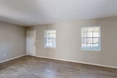 Located at 6042 N Lee St in Morrow, Georgia, this two-story, three-bedroom, two-bathroom home offers a practical and comfortable layout spread evenly across two floors. The main level features an open living room and a separate dining room, both finished with light-toned wood-look flooring that runs throughout the common areas. Neutral beige walls and multiple windows allow natural light to fill the space, creating a bright and airy atmosphere. The kitchen is equipped with warm wood cabinetry, a tile backsplash, electric range, and stainless steel refrigerator, complemented by continued wood-look flooring. A dedicated laundry area and multiple hallways connect the main living spaces efficiently. Upstairs, the three bedrooms are carpeted for comfort, each featuring windows that bring in natural light and views of the surrounding area. The primary bedroom offers generous proportions with ample room for furnishings. The bathrooms are finished with light tile flooring, white vanities, and windows for natural ventilation. With six closets distributed throughout the home, storage is plentiful. The textured ceilings, clean white trim, and consistent neutral palette give the entire home a cohesive, move-in-ready feel.
