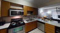 Located at 1009 S Second St in Champaign, Illinois, this two-floor residence offers a functional and practical layout spread across two levels. The kitchen is well-equipped with stainless steel appliances, including a side-by-side refrigerator with ice maker, electric range, microwave, and dishwasher. Warm oak cabinetry provides ample storage, while light tile flooring and a double-basin sink complete the space. A peninsula with bar seating connects the kitchen to the living area, which features a striking wrought-iron spiral staircase serving as both a functional and architectural centerpiece. Multiple bedrooms are distributed across both floors, each carpeted and sized to comfortably accommodate a bed and desk. Several bedrooms include built-in shelving or closet storage, and windows with blinds allow for natural light. The bathrooms are finished with tile flooring and include pedestal or vanity sinks, shower-tub combinations, and overhead cabinetry for storage. The overall layout is efficient and straightforward, offering practical living spaces suitable for multiple occupants. The two-level design, highlighted by the spiral staircase, adds a distinctive architectural element to an otherwise classic residential interior.