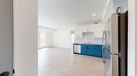 Located at 9998 W Jewell Ave in Lakewood, Colorado, this single-floor, 3-bedroom, 2-bathroom unit offers a clean, modern design with a bright and airy atmosphere throughout. Light wood-style flooring flows seamlessly across every room, complementing the crisp white walls and creating a cohesive, contemporary aesthetic.

The kitchen is a standout feature, showcasing a striking two-tone cabinet design with bold teal lower cabinets and white upper cabinets, paired with light countertops and a white tile backsplash. Stainless steel appliances, including a refrigerator, range, microwave, and dishwasher, complete this well-equipped space, which opens directly to the living area.

The living room benefits from generous natural light, courtesy of large windows fitted with vertical blinds that allow for adjustable brightness and outdoor views. Each of the three bedrooms continues this bright, open feel, with multiple windows framing views of the surrounding greenery. The primary bedroom is notably spacious, offering ample room for a full furniture arrangement.

Both bathrooms are finished with the same light wood flooring and feature teal vanity cabinets with marble-style countertops, undermount sinks, and a combined tub and shower. One bathroom includes a sleek glass panel door, adding a modern touch. A dedicated closet provides additional storage within the unit.
