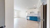 Located at 9998 W Jewell Ave in Lakewood, Colorado, this single-floor, 3-bedroom, 2-bathroom unit offers a clean, modern design with a bright and airy atmosphere throughout. Light wood-style flooring flows seamlessly across every room, complementing the crisp white walls and creating a cohesive, contemporary aesthetic.

The kitchen is a standout feature, showcasing a striking two-tone cabinet design with bold teal lower cabinets and white upper cabinets, paired with light countertops and a white tile backsplash. Stainless steel appliances, including a refrigerator, range, microwave, and dishwasher, complete this well-equipped space, which opens directly to the living area.

The living room benefits from generous natural light, courtesy of large windows fitted with vertical blinds that allow for adjustable brightness and outdoor views. Each of the three bedrooms continues this bright, open feel, with multiple windows framing views of the surrounding greenery. The primary bedroom is notably spacious, offering ample room for a full furniture arrangement.

Both bathrooms are finished with the same light wood flooring and feature teal vanity cabinets with marble-style countertops, undermount sinks, and a combined tub and shower. One bathroom includes a sleek glass panel door, adding a modern touch. A dedicated closet provides additional storage within the unit.