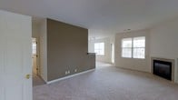 Located at 80 Jefferson Blvd in Fishkill, NY, this single-floor residence offers three bedrooms and two bathrooms within a thoughtfully laid-out floor plan. The main living area is generously sized, featuring plush wall-to-wall carpeting and a clean, neutral color palette that creates a bright and welcoming atmosphere. A distinctive taupe accent wall serves as a natural divider within the open living space, adding architectural interest while subtly defining separate functional zones. Track lighting overhead provides flexible illumination, complementing the abundant natural light that pours in through multiple large windows. The windows frame views of the surrounding exterior, enhancing the sense of openness throughout. A built-in breakfast bar or pass-through counter connects the living area to an adjoining space, offering both practicality and a casual dining option. The crisp white ceilings and light-toned walls throughout contribute to an airy, well-lit environment. The overall design emphasizes a straightforward, functional layout that balances comfort with practicality, making it well-suited for everyday living. Its single-level design ensures seamless flow between spaces, while the neutral finishes provide a versatile backdrop for a variety of interior styles.