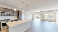 Located at 240 Thompson Ave E in West St. Paul, MN, this well-appointed 3-bedroom, 2-bathroom residence offers a thoughtfully designed single-floor layout with a bright, open feel throughout. The combined kitchen and living area serves as the heart of the home, where rich dark-stained cabinetry, white subway tile backsplash, quartz countertops, and stainless steel appliances create a polished, functional kitchen. A large island with pendant lighting anchors the space, flowing seamlessly into the living area, which features light hardwood-style flooring and sliding glass doors that open to a private balcony with tree-lined outdoor views. Natural light pours in through generously sized windows, enhancing the airy atmosphere of the main living space. The primary bedroom is well-sized, complete with plush carpeting, a ceiling fan, and a large window with outdoor views. It is complemented by a spacious walk-in closet featuring built-in shelving and hanging rods on both sides. The primary bathroom boasts a dual-sink vanity with a blue-toned cabinet, quartz countertop, and a wide mirror with modern lighting. Additional bedrooms are carpeted and comfortably sized. The residence also includes a dedicated laundry room, utility room, and ample closet storage throughout.