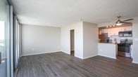 Located at 330 W Brambleton Ave in Norfolk, Virginia, this single-floor residence offers a thoughtfully designed open-concept layout that maximizes both space and functionality. The living area is anchored by smooth, light-toned wood-style flooring that flows seamlessly throughout, creating a cohesive and airy atmosphere. A wall of floor-to-ceiling sliding glass doors floods the living space with abundant natural light and opens directly onto a private balcony, offering expansive outdoor views of the surrounding Norfolk skyline.

The kitchen is a standout feature, showcasing granite countertops with warm, earthy tones, white cabinetry, a classic subway tile backsplash, and stainless steel appliances including a gas range, built-in microwave, and refrigerator. A raised breakfast bar peninsula connects the kitchen to the living area, making it ideal for casual dining or entertaining. A walk-in closet provides generous storage off the main living space.

The bathroom is clean and functional, featuring a tub-shower combination with a decorative curtain rod and textured walls that add subtle character. A ceiling fan with a pendant-style light fixture adds a practical touch to the kitchen nook area. The unit's neutral color palette, modern finishes, and access to natural light make it a welcoming and versatile living space.