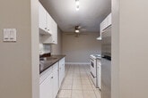 This well-appointed one-bedroom, one-bathroom unit in Surrey, BC offers a practical and comfortable layout across a single floor. The galley-style kitchen is efficiently designed with white cabinetry, dark granite-style countertops, a tile backsplash, stainless steel refrigerator, and white electric range. Light tile flooring and a ceiling fan carry through into the adjacent dining area, creating a cohesive and functional space. The open living room features updated grey laminate flooring, neutral warm-toned walls, a baseboard heater, and a large sliding glass door that floods the room with natural light and provides direct access to a private balcony with views of surrounding greenery. The spacious bedroom is finished with light laminate flooring, soft neutral walls, and a built-in closet with bifold doors offering ample storage. The bathroom is finished with tile flooring, a white vanity with dark countertop, a large mirror, and chrome fixtures. Throughout the unit, clean lines, neutral tones, and updated finishes contribute to a bright, move-in-ready atmosphere that is both practical and inviting.