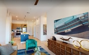 Located at 4475 Scott Robinson Blvd #2127 in Las Vegas, NV, this modern 2-bedroom, 2-bathroom apartment offers 930 square feet of thoughtfully designed living space on a single floor. The kitchen is a standout feature, showcasing light wood cabinetry extending to the ceiling, a marble-style backsplash, stainless steel appliances including a gas range and refrigerator, and a bold blue-accented island with a white quartz countertop and pendant lighting overhead. Light hardwood-style flooring flows throughout the main living areas. The living room is bright and inviting, with tall ceilings, large sliding glass doors opening to a private balcony with outdoor views, and a ceiling fan. The primary bedroom measures 150 square feet and features high ceilings, a ceiling fan, and generous natural light. The second bedroom includes a striking accent wall. Both bathrooms are finished with floating wood vanities, backlit mirrors, white quartz countertops, and full tub-shower combinations with tiled surrounds. The unit also includes two closets for ample storage. The overall ambiance is contemporary and clean, with a cohesive modern aesthetic carried throughout every room.