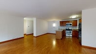 Located along North Sheridan Road in Chicago's vibrant Lakeview neighborhood, this single-floor residence offers a clean, modern aesthetic defined by warm hardwood flooring, crisp white walls, and generous natural light throughout. The expansive living area is a standout feature, wrapped in floor-to-ceiling windows and sliding glass doors that frame tree-lined street views and flood the interior with sunlight. The open layout flows seamlessly, with a defined corridor connecting the living spaces to the more private areas of the unit. A sliding barn-style door adds a contemporary touch near the entryway. The kitchen is well-appointed with rich wood cabinetry, granite countertops, a classic subway tile backsplash, and a full suite of stainless steel appliances, including a range, built-in microwave, and dishwasher. A peninsula provides additional prep space and visual separation from the main living area. The bedroom offers a quiet retreat with hardwood floors, white walls, and a large closet with sleek sliding doors. Wall-mounted sconces provide warm accent lighting throughout. The unit's consistent design language—neutral tones, polished floors, and abundant glazing—creates a bright, cohesive, and inviting living environment.