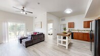 Located at 715 Monnett Ave in Norman, Oklahoma, this single-floor home offers four bedrooms and three bathrooms within a thoughtfully arranged layout. Light wood-style flooring runs throughout, creating a cohesive and airy feel across the entire space.

The open-concept kitchen and living area serves as the heart of the home. The kitchen is well-appointed with rich warm-toned cabinetry, granite-style countertops, a mosaic tile backsplash, a double-basin sink, and a full suite of black appliances including a refrigerator with ice dispenser, range, microwave, and dishwasher. A freestanding island with a butcher-block top provides additional prep and seating space.

The adjoining living room features soaring vaulted ceilings, a ceiling fan, and a sliding glass door that opens to a private balcony, flooding the space with natural light and outdoor views. A hallway connects the living area to the bedrooms and bathrooms, maintaining a clear and functional flow.

The primary bedroom offers generous proportions, vaulted ceilings, and a double-door closet. The bathrooms feature tile flooring, tiled tub-shower combinations, and white vanities with ample storage. A dedicated laundry room houses a full-size washer and dryer along with overhead shelving, adding everyday convenience to this well-equipped home.