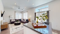 Located in Castle Pines, Colorado, this modern single-floor residence offers a thoughtfully designed 2-bedroom, 2-bathroom layout with a clean, contemporary aesthetic throughout. Wide-plank wood-look flooring and recessed lighting flow seamlessly from room to room, creating a cohesive and inviting atmosphere.

The open-concept kitchen is a standout feature, showcasing light wood cabinetry, a white subway tile backsplash, stainless steel appliances, and a generous island with quartz-style countertops and bar seating — ideal for both everyday meals and entertaining. The kitchen opens directly into the living room, which is bathed in natural light from multiple large windows framed by sheer curtains. A ceiling fan adds comfort to the airy space.

A welcoming entryway hallway with wall-mounted hooks leads efficiently through the home, with in-unit laundry conveniently accessible along the corridor. The primary bedroom features a distinctive teal accent wall, wood-look flooring, a ceiling fan, and soft natural light. The second bedroom is bright and neutral, with windows providing ample daylight. Both bathrooms are finished with light wood cabinetry, quartz countertops, and wood-look tile flooring, with one featuring a full tub-shower combination.