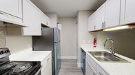 Located at 550 Hay Mac Dr in Parchment, Michigan, this single-floor unit presents a clean, modern aesthetic with updated finishes throughout. The living area is a standout feature, offering generous open space finished with smooth gray wood-look flooring that reflects natural light streaming in through large sliding glass doors fitted with vertical blinds. The layout connects seamlessly to a hallway leading toward the rest of the unit, enhancing the sense of flow.

The galley-style kitchen is well-appointed with white shaker cabinetry, brushed nickel hardware, light quartz-style countertops, and a full suite of stainless steel appliances including a refrigerator, range, and dishwasher. A stainless undermount sink completes the functional workspace.

The bedrooms are carpeted in warm neutral tones and receive natural light through blinded windows. One bedroom features dual doorways, providing flexible access to adjoining spaces. The bathrooms are finished with wood-look vinyl flooring, white vanity cabinetry, and mirrored medicine cabinets. Grab bars are present in both bathrooms, reflecting accessible design considerations. Overall, the unit presents a cohesive, neutral palette throughout.